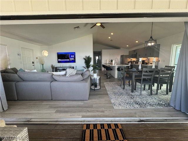 living room featuring sink, lofted ceiling, ceiling fan with notable chandelier, and dark hardwood / wood-style flooring