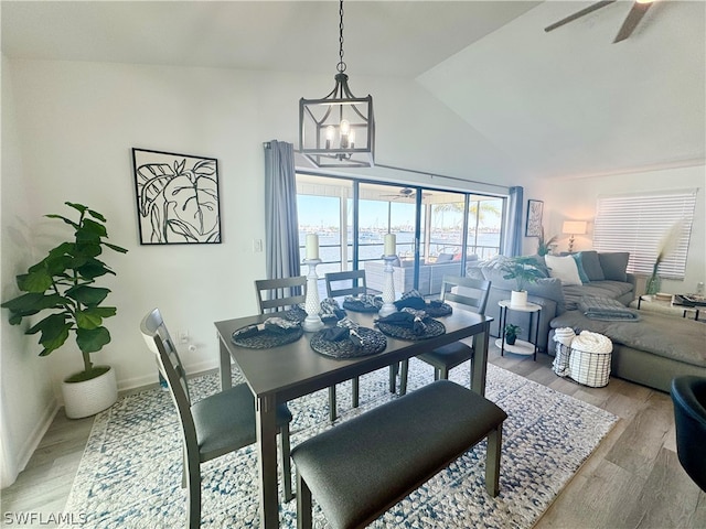 dining room with light hardwood / wood-style flooring, ceiling fan with notable chandelier, and lofted ceiling