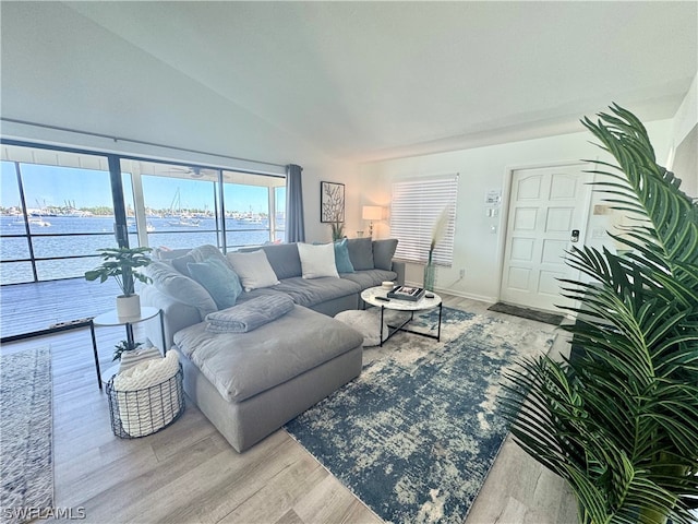 living room featuring a water view, light hardwood / wood-style floors, and vaulted ceiling