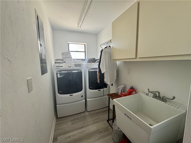 laundry room featuring cabinets, separate washer and dryer, sink, and light wood-type flooring