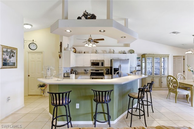 kitchen featuring ceiling fan, a breakfast bar, lofted ceiling, and appliances with stainless steel finishes