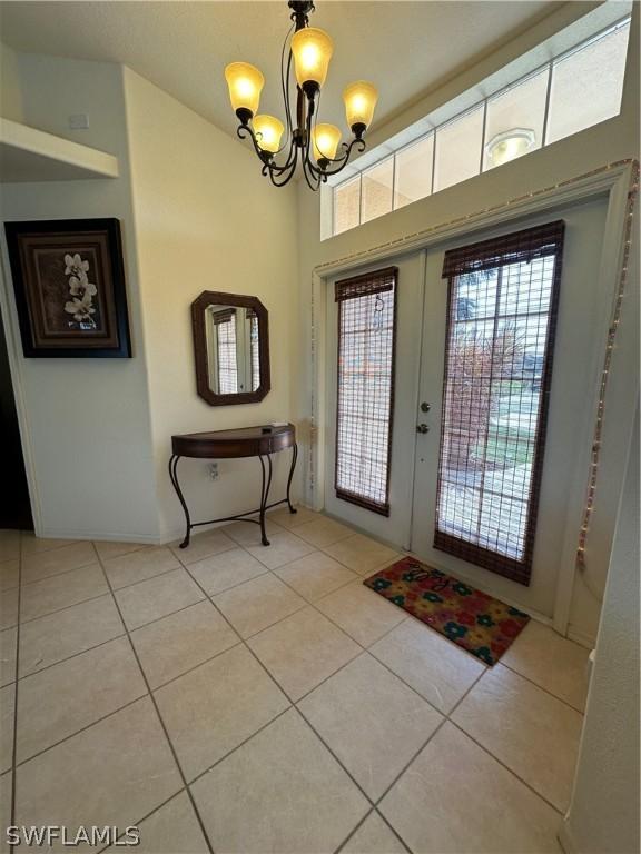 tiled foyer featuring french doors and a chandelier