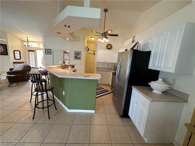 kitchen featuring light tile patterned floors, an island with sink, a kitchen bar, white cabinets, and ceiling fan with notable chandelier