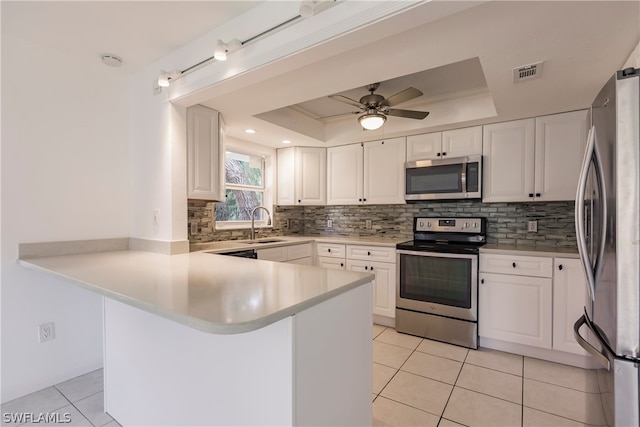 kitchen with white cabinets, ceiling fan, appliances with stainless steel finishes, and a tray ceiling