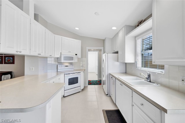 kitchen featuring kitchen peninsula, white appliances, white cabinetry, and sink