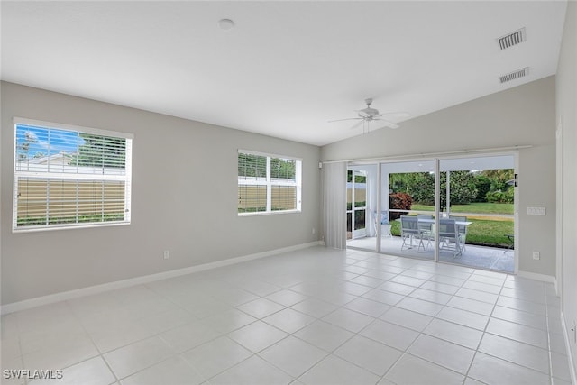 spare room with ceiling fan, a wealth of natural light, lofted ceiling, and light tile patterned floors