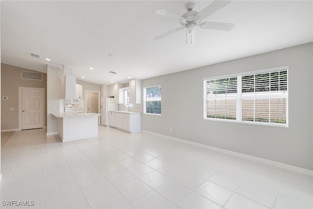 unfurnished living room featuring sink, light tile patterned floors, a healthy amount of sunlight, and lofted ceiling