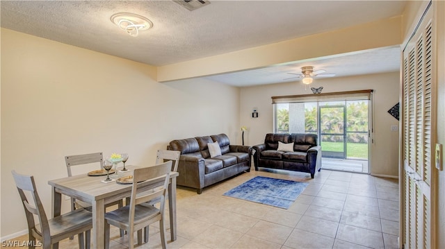 tiled living room with a textured ceiling and ceiling fan