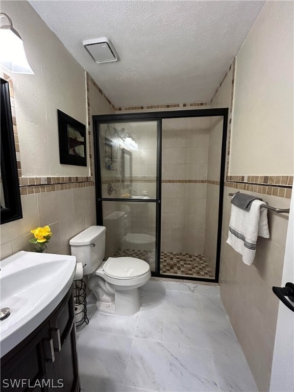 bathroom featuring vanity, walk in shower, tile walls, a textured ceiling, and toilet