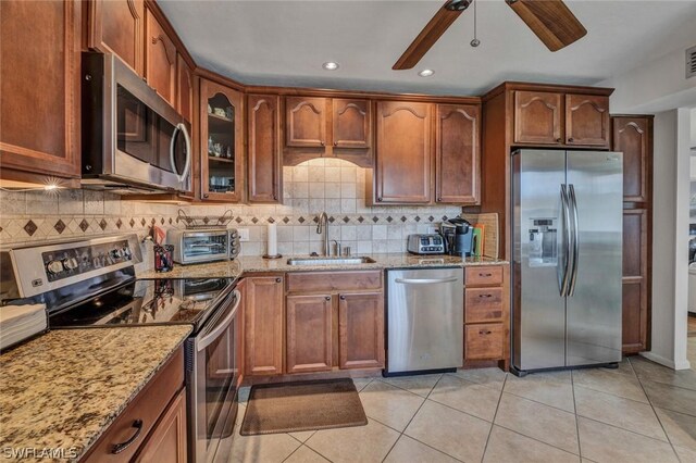 kitchen with backsplash, ceiling fan, appliances with stainless steel finishes, and light tile floors