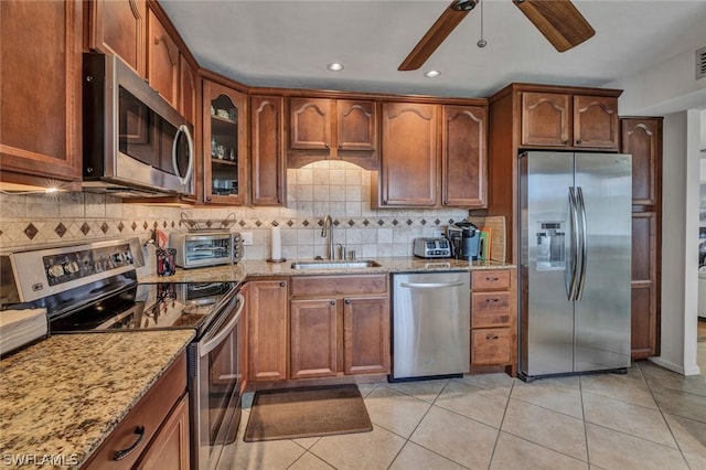 kitchen featuring light tile patterned flooring, sink, light stone counters, appliances with stainless steel finishes, and ceiling fan