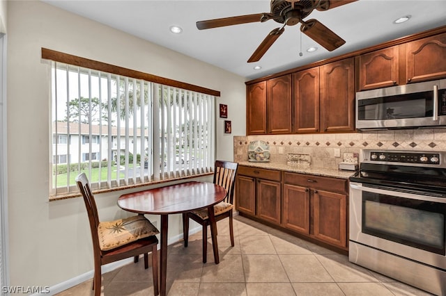 kitchen featuring stainless steel appliances, light tile floors, light stone countertops, ceiling fan, and tasteful backsplash