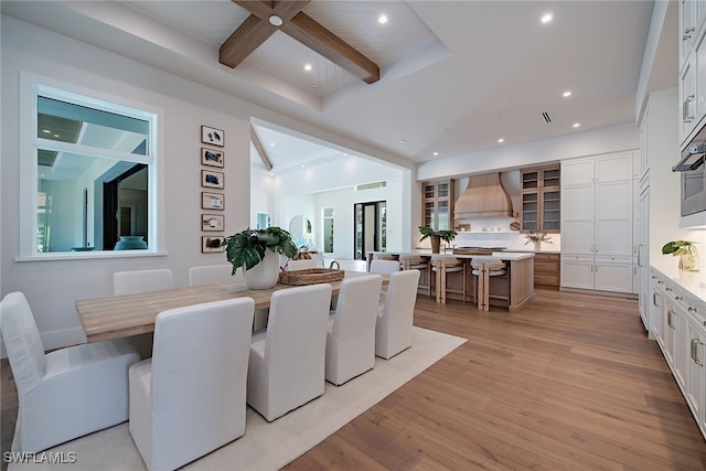 dining room featuring beam ceiling and light hardwood / wood-style flooring