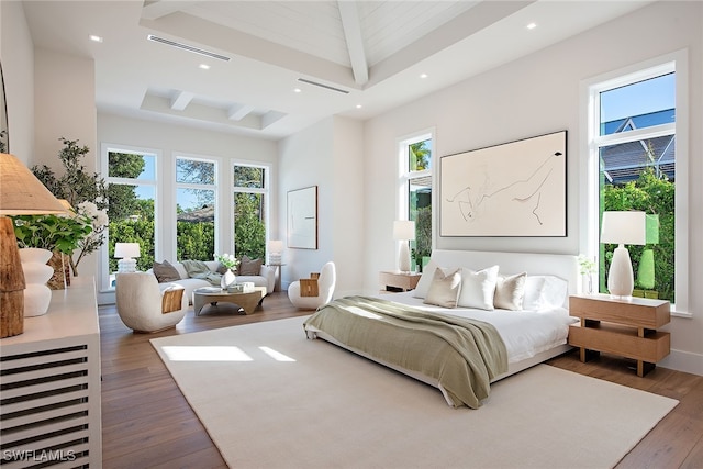 bedroom with dark wood-type flooring, a towering ceiling, multiple windows, and beam ceiling