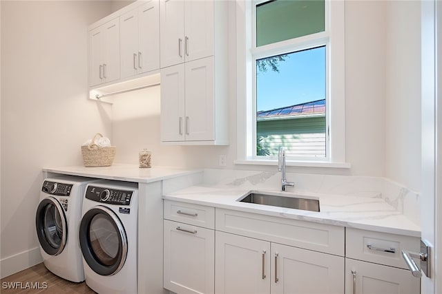 washroom featuring washing machine and clothes dryer, cabinets, sink, and hardwood / wood-style floors