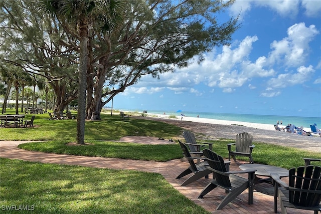 surrounding community featuring a lawn, a beach view, and a water view