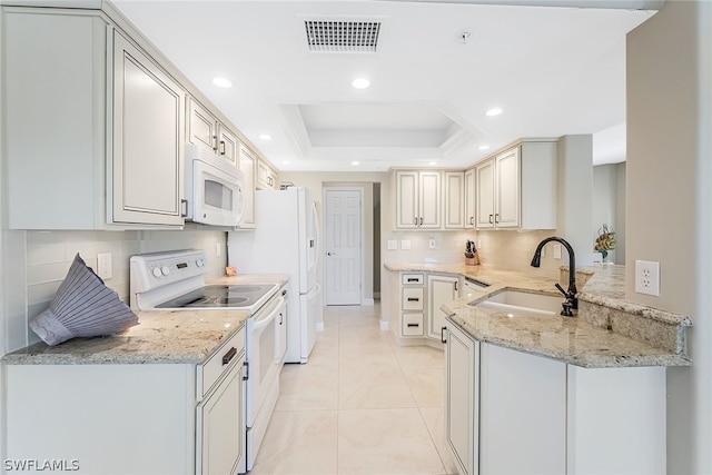 kitchen featuring white appliances, sink, light stone counters, light tile flooring, and a tray ceiling