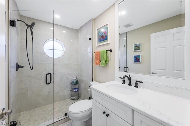 bathroom featuring a shower with shower door, vanity with extensive cabinet space, and toilet