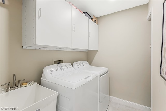 laundry area with cabinets, light tile flooring, sink, and washing machine and dryer