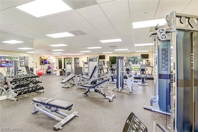 gym featuring a paneled ceiling and a healthy amount of sunlight