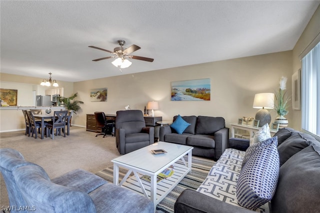carpeted living room featuring a textured ceiling and ceiling fan with notable chandelier