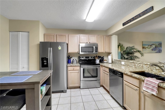 kitchen with light brown cabinets, stainless steel appliances, and sink