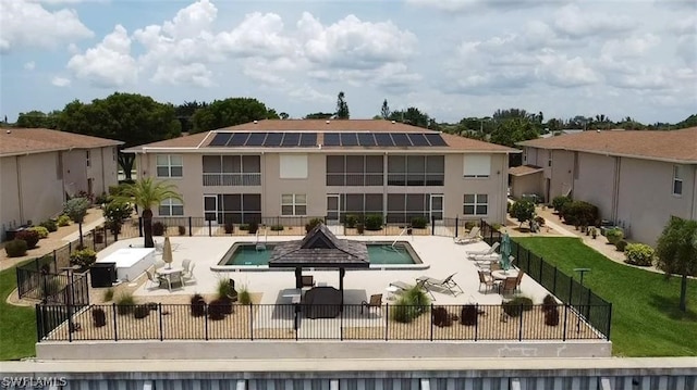 back of property featuring a community pool, a lawn, a patio area, and solar panels