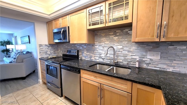 kitchen featuring dark stone countertops, tasteful backsplash, sink, appliances with stainless steel finishes, and light hardwood / wood-style floors