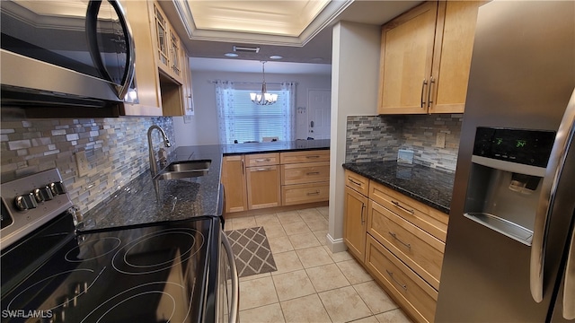 kitchen featuring decorative light fixtures, appliances with stainless steel finishes, a notable chandelier, sink, and a tray ceiling