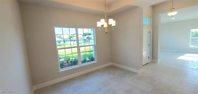 unfurnished room featuring a wealth of natural light and a notable chandelier