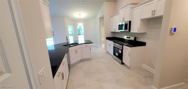 kitchen with pendant lighting, appliances with stainless steel finishes, kitchen peninsula, sink, and white cabinets