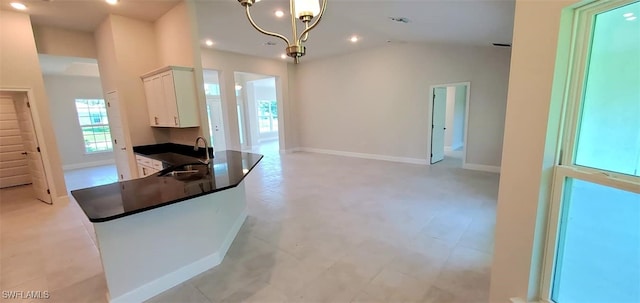 kitchen with a chandelier, white cabinetry, sink, lofted ceiling, and kitchen peninsula