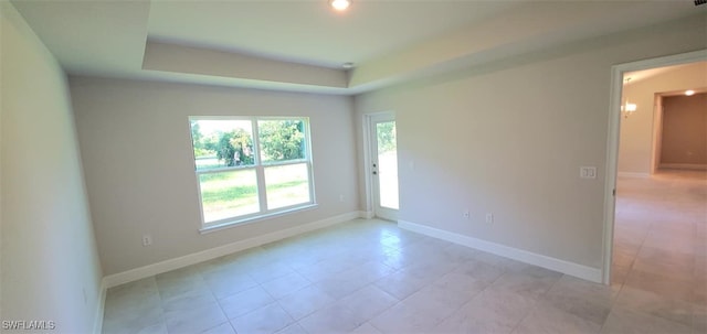 unfurnished room featuring a tray ceiling and light tile patterned flooring