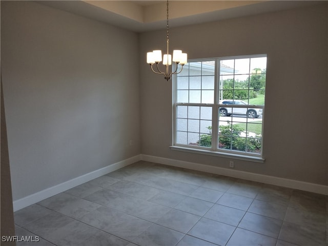 empty room with a notable chandelier and tile patterned floors