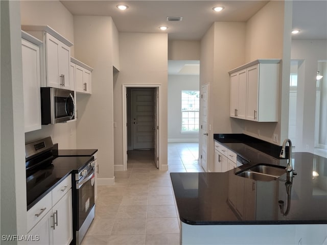 kitchen featuring stainless steel appliances, sink, light tile patterned floors, and white cabinets