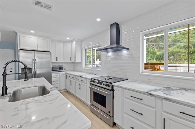 kitchen featuring white cabinetry, stainless steel appliances, light stone countertops, wall chimney exhaust hood, and sink