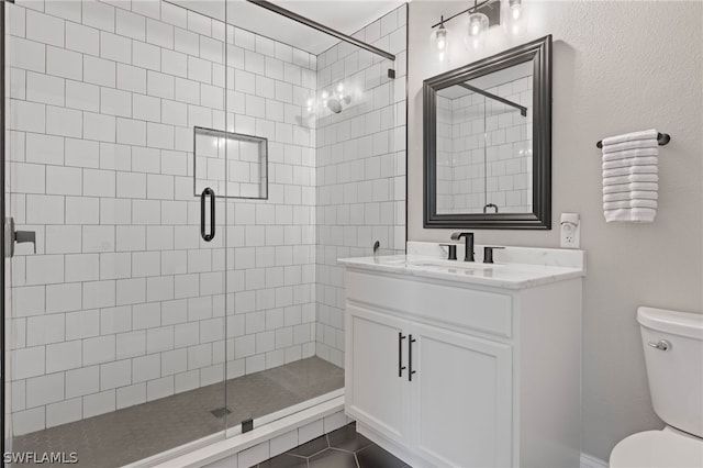 bathroom featuring toilet, tile patterned flooring, a shower with door, and vanity