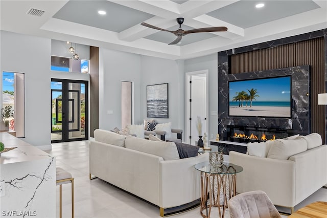 tiled living room featuring coffered ceiling, ceiling fan, french doors, and a high end fireplace