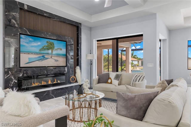 living room with a high end fireplace and a raised ceiling