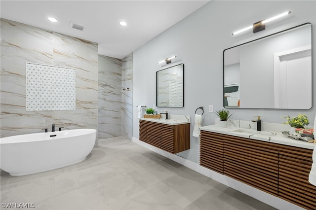 bathroom with tile floors, dual vanity, a bathing tub, and tile walls