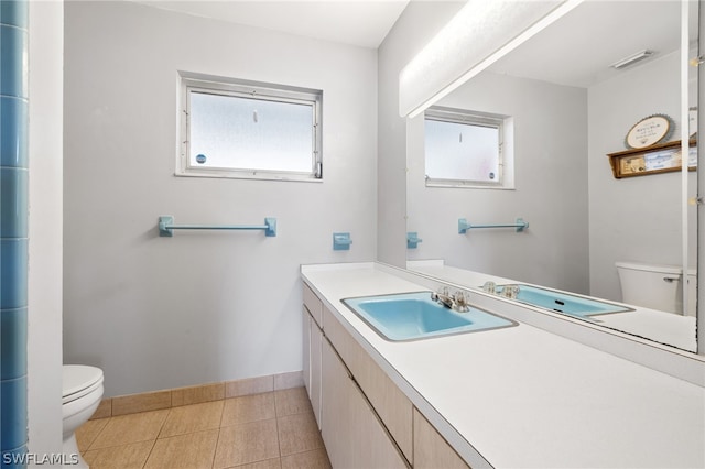 bathroom with toilet, tile flooring, large vanity, and a wealth of natural light