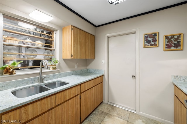 kitchen featuring crown molding, light stone countertops, sink, and light tile floors