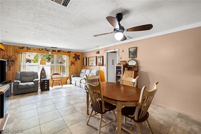 tiled dining area featuring crown molding, a textured ceiling, and ceiling fan