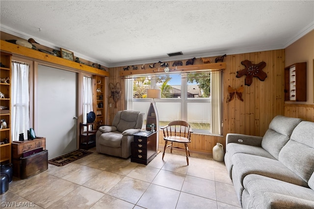 living room featuring ornamental molding, a textured ceiling, wood walls, and light tile floors