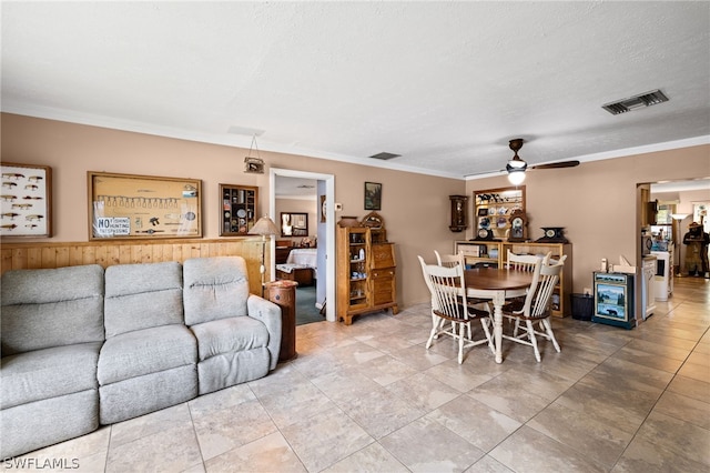 living room featuring light tile floors, ceiling fan, a textured ceiling, and crown molding