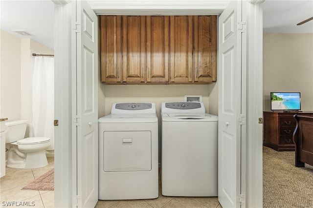 washroom featuring washer and dryer, light tile flooring, ceiling fan, and cabinets