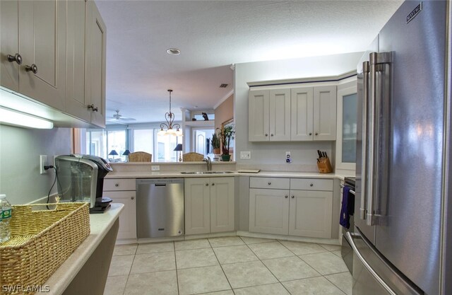 kitchen with sink, decorative light fixtures, light tile patterned flooring, and appliances with stainless steel finishes