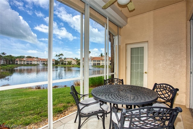 sunroom with ceiling fan, a healthy amount of sunlight, and a water view