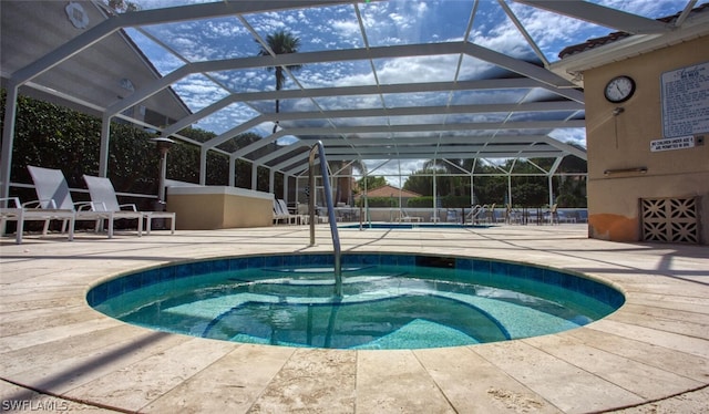 view of pool featuring glass enclosure, a patio area, and a hot tub