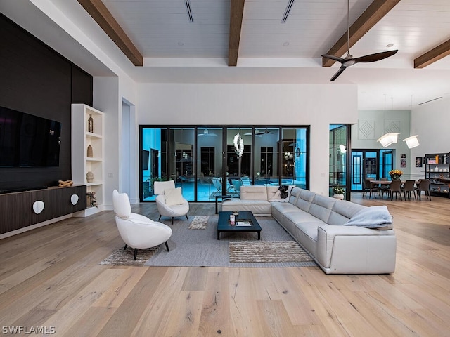 living room featuring a high ceiling, light hardwood / wood-style floors, ceiling fan, and beamed ceiling